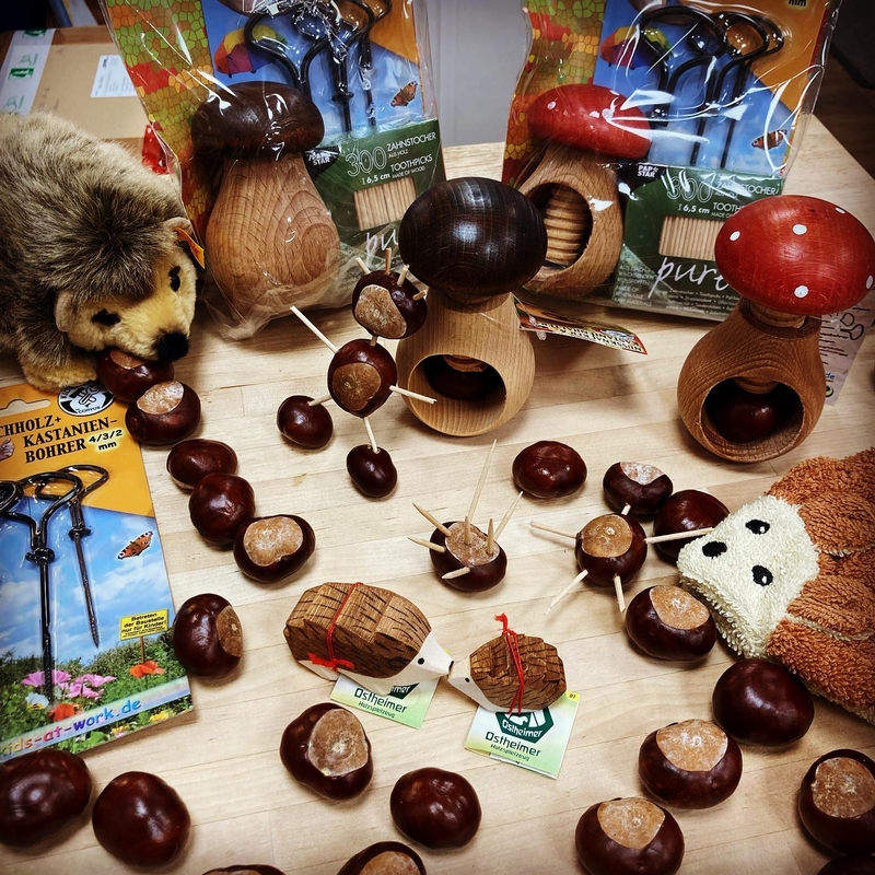Ein herbstliches Arrangement mit Kastanien und verschiedenem Holz, sowie Plüschspielzeug in Form von Igeln.