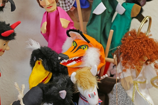 Eine Auswahl von Handpuppen, im Fokus des Bildes ist ein frech anmutender Fuchs.
